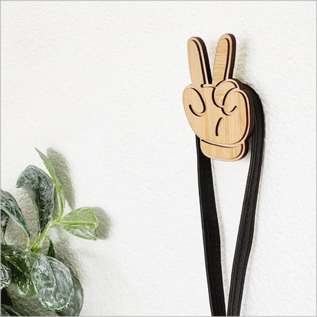 Eco-friendly bamboo wall hook featuring a charming peace hand design, ideal for organizing baby clothes and bags.