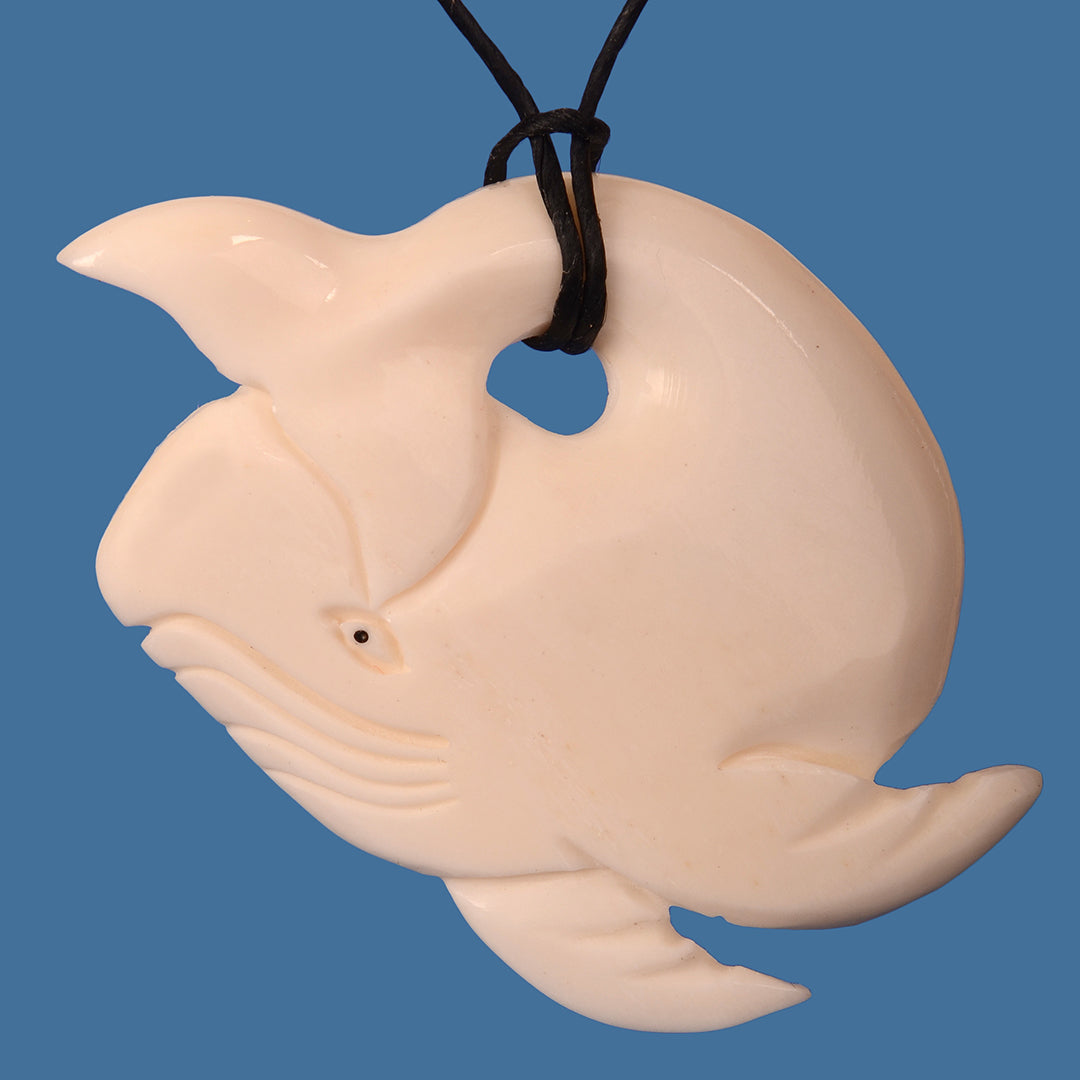 Intricately carved Bone Whale Pendant symbolizing strength and compassion, hung on an adjustable black wax cord.