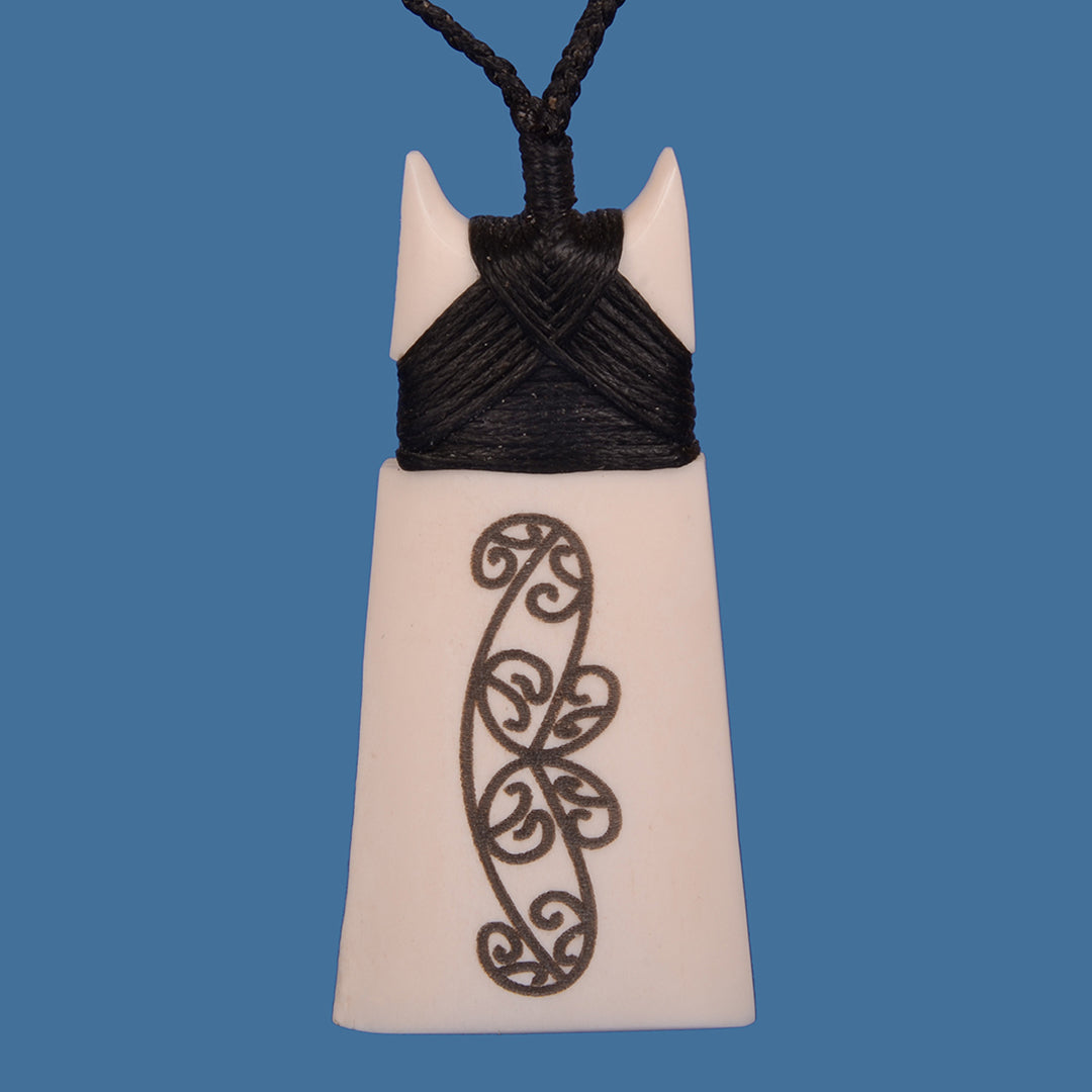 Handcrafted Bone Toki pendant with lasered Kowhaiwhai design on adjustable black cord, symbolizing strength and resilience.