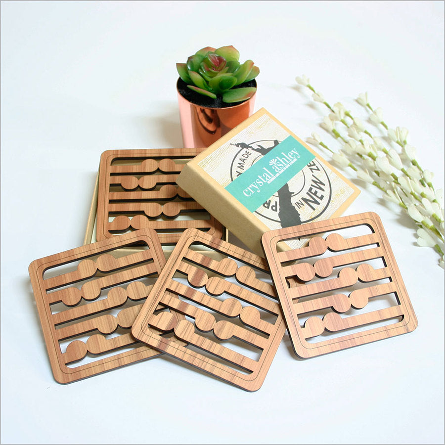 Set of four Rimu wood coasters with intricate koru pattern, showcasing New Zealand craftsmanship and style.