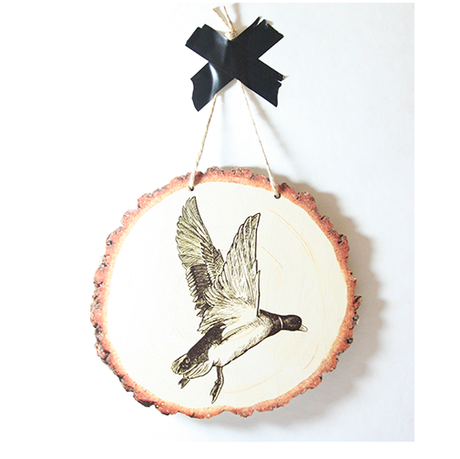Elegant wall art of a flying duck on eco-friendly wood slice, ideal for enhancing rustic or modern interiors.