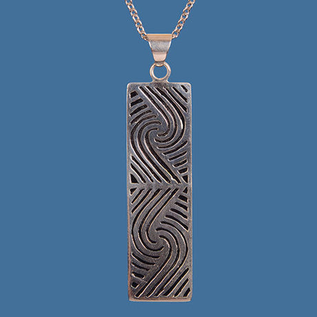 Handcrafted Maori design pendant in brass with silver plating, showcasing New Zealand's cultural heritage.