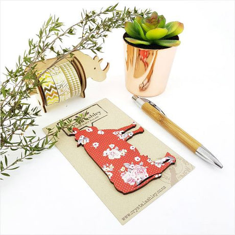 Charming wall art featuring a cow with vibrant red florals, perfect for rustic and contemporary decor styles.