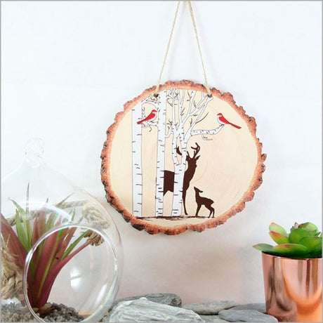 Wood slice wall art featuring a detailed deer amidst a tranquil woodland scene, perfect for nature lovers.
