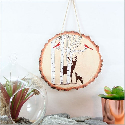 Wood slice wall art featuring a detailed deer amidst a tranquil woodland scene, perfect for nature lovers.