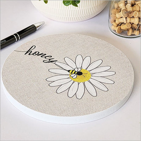 Circular canvas wall art featuring a honey bee on a vibrant daisy, 15cm diameter, perfect for home decor.
