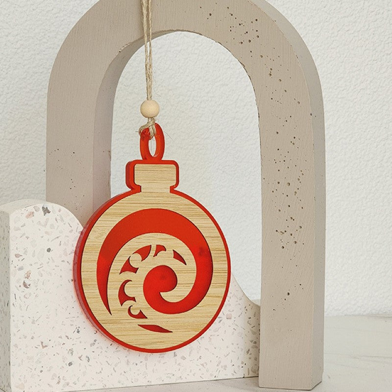 Red satin acrylic hanging ornament featuring a laser-cut Koru design, perfect for festive decor and gifting.