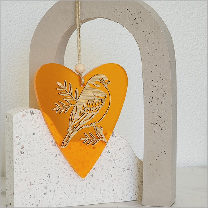 Vibrant orange heart-shaped ornament featuring sparrow and pihoihoi designs, made from eco-friendly acrylic and bamboo.