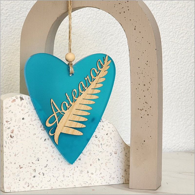 Teal satin acrylic heart ornament featuring laser-cut silver fern design, perfect for home decor and gifts.