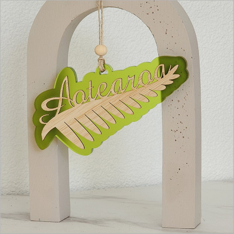 Lime satin acrylic hanging ornament featuring a laser-cut silver fern design, perfect for home or office decor.