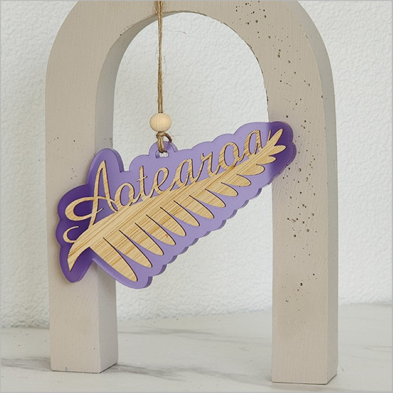 Purple satin acrylic hanging ornament in the shape of a silver fern, made from laser-cut bamboo.