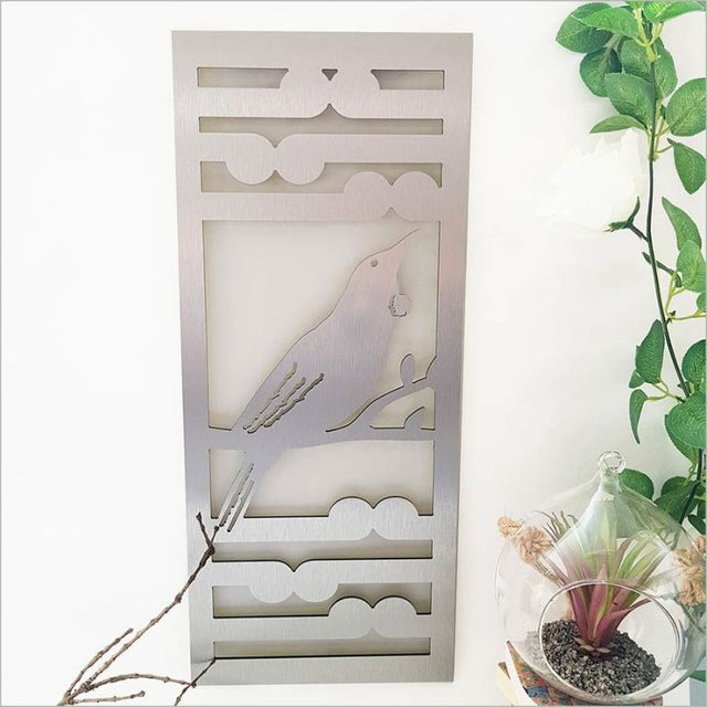 Brushed silver wall art panel featuring Tui bird and Koru fern, 55cm, ideal for indoor and outdoor decor.