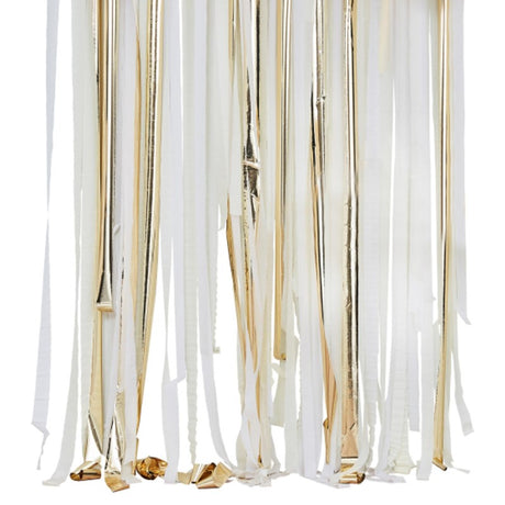 Gold metallic streamers backdrop with white and cream rolls, perfect for elegant party decor and photo booths.