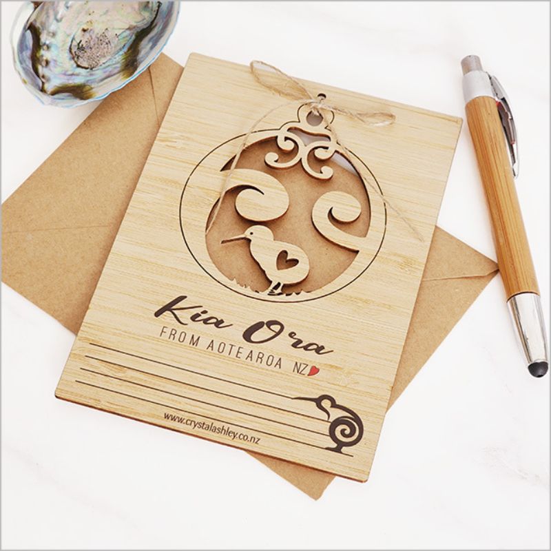 Bamboo postcard featuring Kia Ora Kiwi design, eco-friendly, perfect for greetings or as a unique hanging decoration.