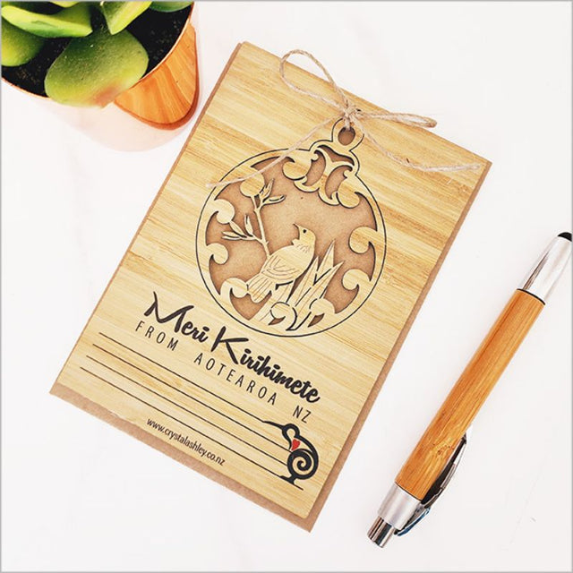 Eco-friendly bamboo postcard with Tui design for Meri Kirihimete, includes jute string and craft envelope.
