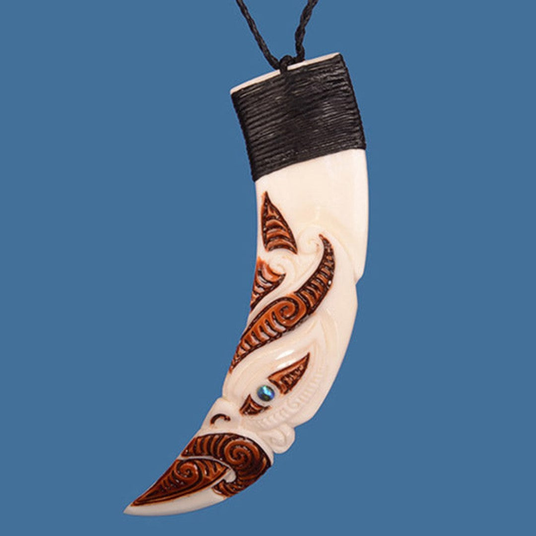 Handcrafted stained pig tusk pendant featuring a vibrant Manaia design with P?ua shell eye, on an adjustable wax cord.