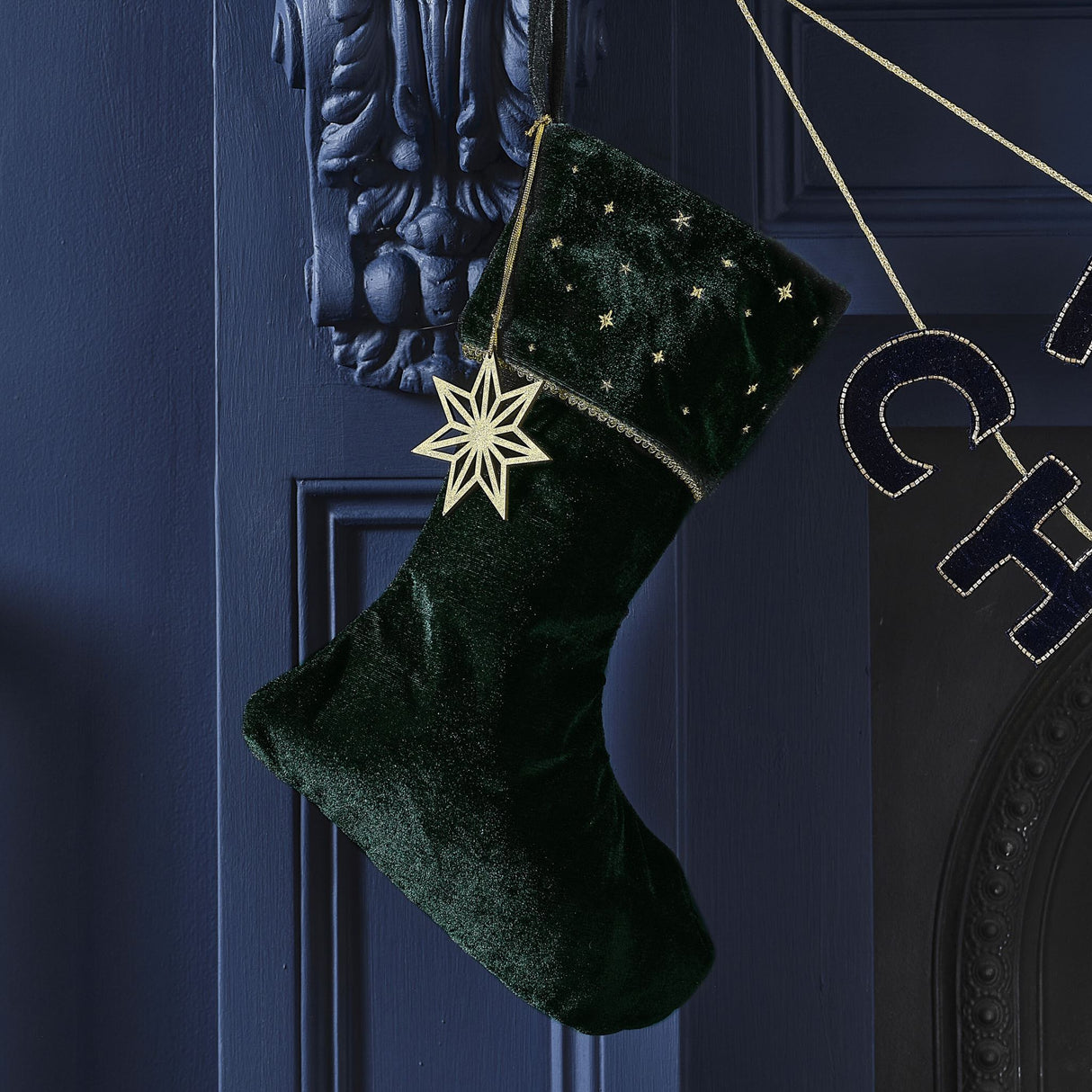 Luxurious green velvet Christmas stocking embroidered with a gold star charm, perfect for festive decor and sustainable traditions.