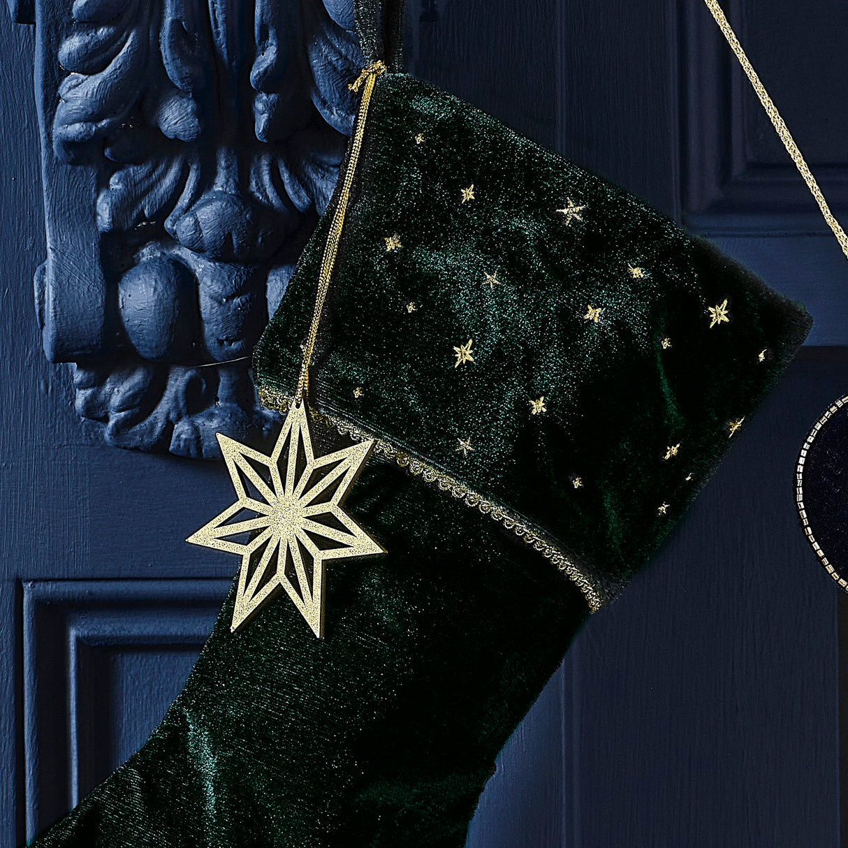 Luxurious green velvet Christmas stocking, embroidered with charm and wooden gold star, perfect for festive decor and reuse.