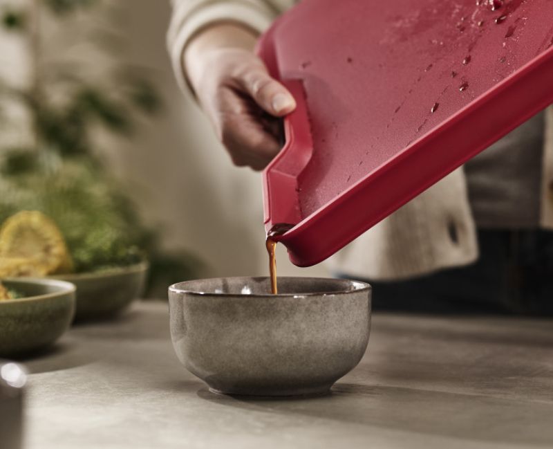 Joseph Joseph Cut & Carve Plus Large Red chopping board with angled base, non-slip edges, and integrated meat grip for easy use.