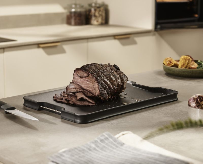 Joseph Joseph Cut & Carve Plus XL Black chopping board with angled base, integrated meat grip, and easy-pour corners for mess-free use.