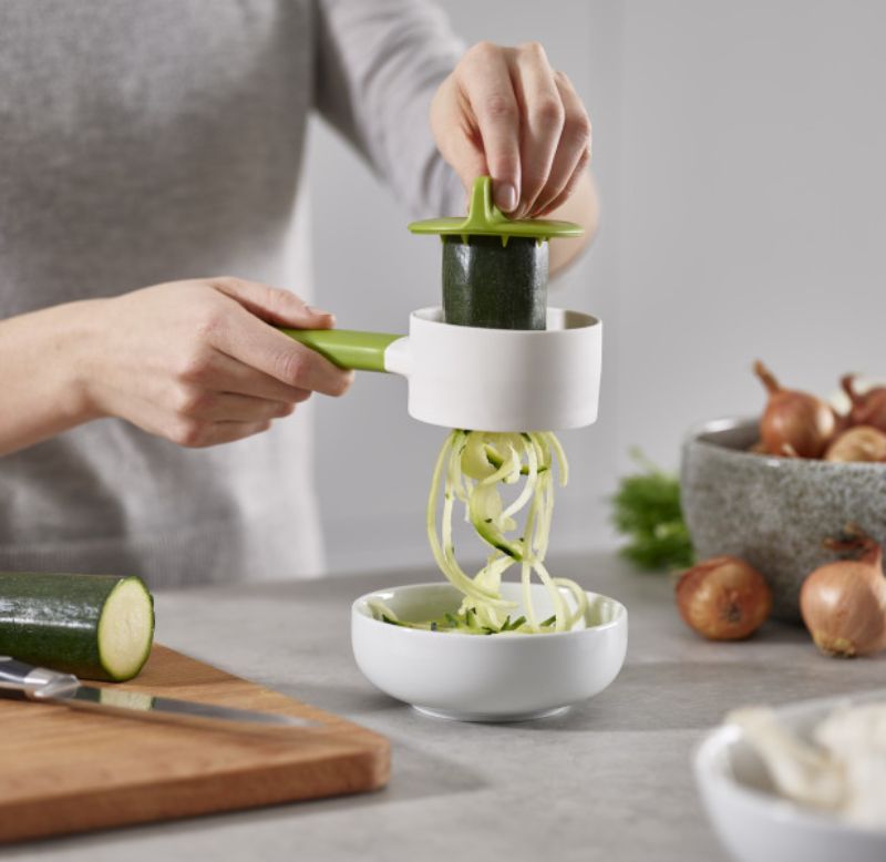 Joseph Joseph SpiroGo Compact Spiralizer in green, designed for quick and easy vegetable spiralizing with safety features.