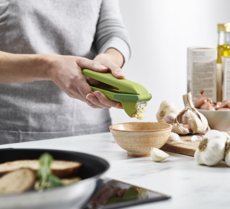 Joseph Joseph Cleanforce Garlic Press with easy-squeeze mechanism and built-in wiper for effortless garlic preparation.