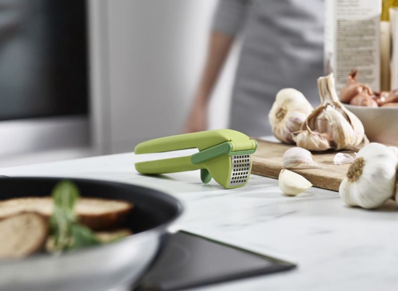 Joseph Joseph Cleanforce Garlic Press with ergonomic handles and built-in wiper for easy garlic crushing and cleaning.