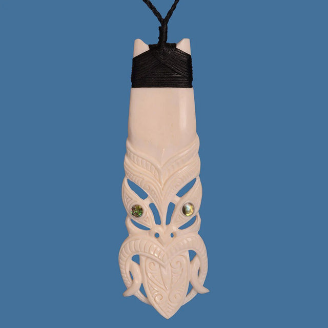 Hand-carved Bone Toki pendant with Tiki pattern, symbolizing Maori craftsmanship and resilience, on adjustable cord.