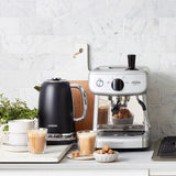 Sleek silver Sunbeam Mini Barista Espresso Machine with 1350W power, 15-bar pump, and 2L water tank for home brewing.