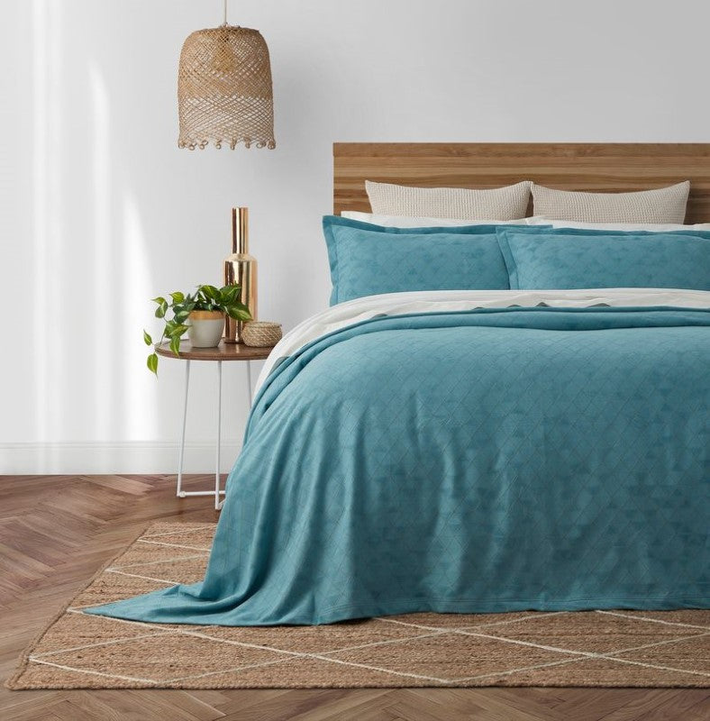 Nelle Bedspread by BAKSANA featuring a blue geometric pattern with gold accents, designed for Super King beds.