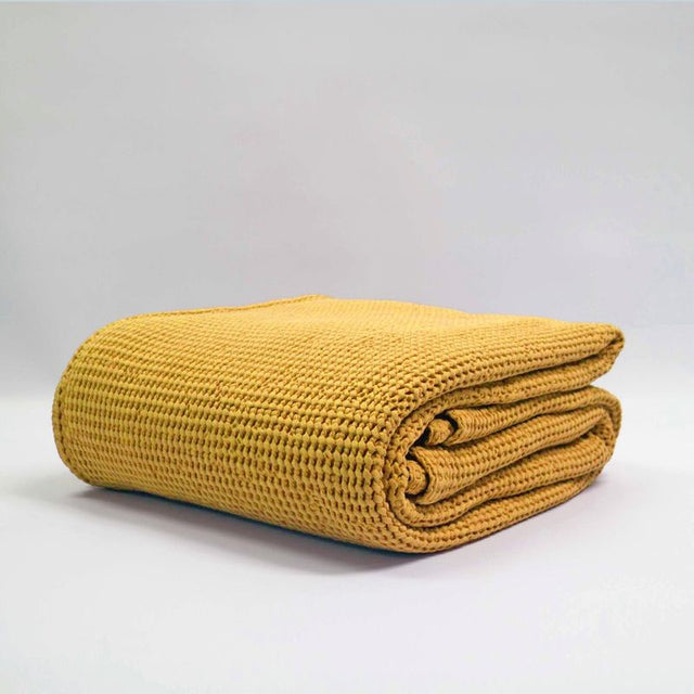 Large stonewashed blanket in turmeric color, featuring deep waffle texture, made from 100% OEKO-TEX® certified cotton.