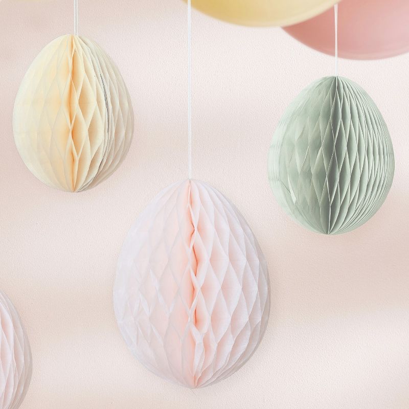 Colorful honeycomb Easter egg decorations in cream, light pink, and sage green, perfect for festive hanging decor.