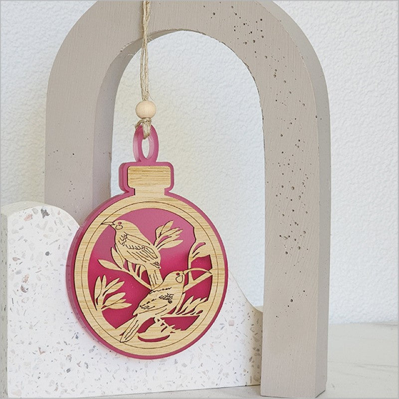 Elegant pink satin acrylic bauble with intricate laser-cut bamboo design, perfect for holiday decor and year-round charm.