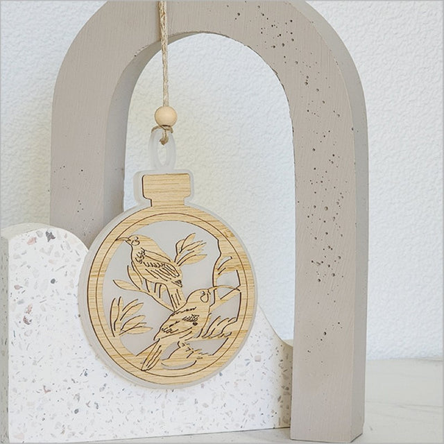Elegant white acrylic bauble ornament with intricate laser-cut designs, perfect for festive decor and easy gifting.