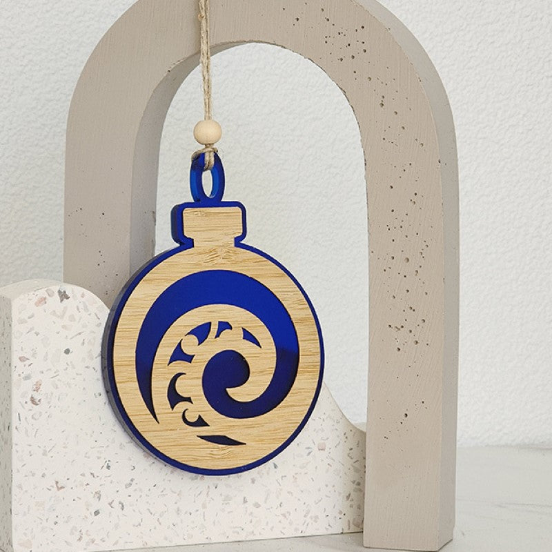 Blue satin acrylic bauble ornament featuring a unique Koru design, perfect for holiday decor and gifts.
