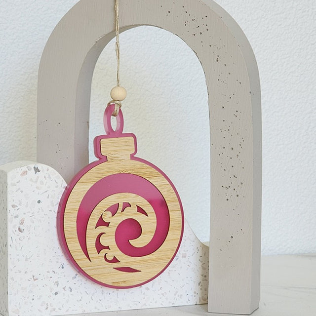 Elegant pink satin acrylic ornament featuring a Koru design, perfect for home decor or gifting.