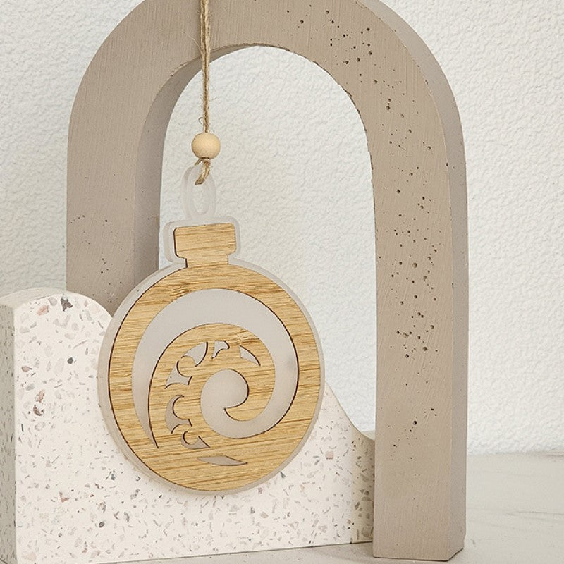 Elegant white satin acrylic hanging ornament featuring a Koru design and laser-cut bamboo accent, perfect for holiday decor.