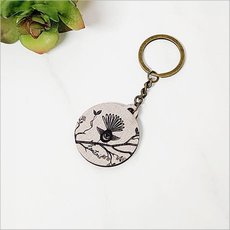Lightweight printed pine keychain featuring a charming Fantail design, perfect for showcasing Kiwiana style.
