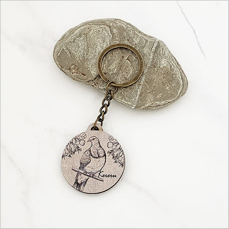 Lightweight printed pine keychain featuring a Kereru and Puriri design, perfect for keys or as a Kiwiana gift.