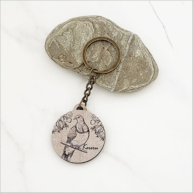Lightweight printed pine keychain featuring a Kereru and Puriri design, perfect for keys or as a Kiwiana gift.