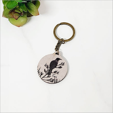 Lightweight pine veneer keychain featuring a Tui bird and flax leaves, 40mm diameter, perfect for stylish key organization.