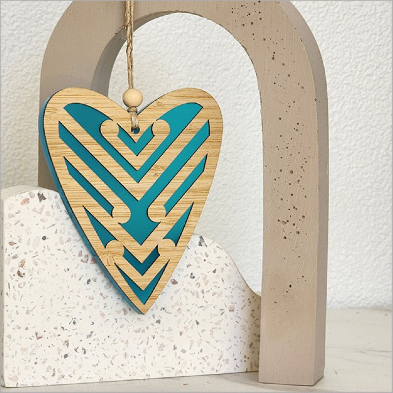Teal satin acrylic heart ornament with laser-cut bamboo Koru design, symbolizing growth and new beginnings.