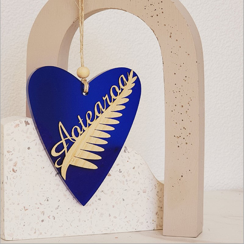 Blue satin acrylic heart ornament featuring a silver fern design, perfect for home decor and gifts, 90mm x 105mm size.