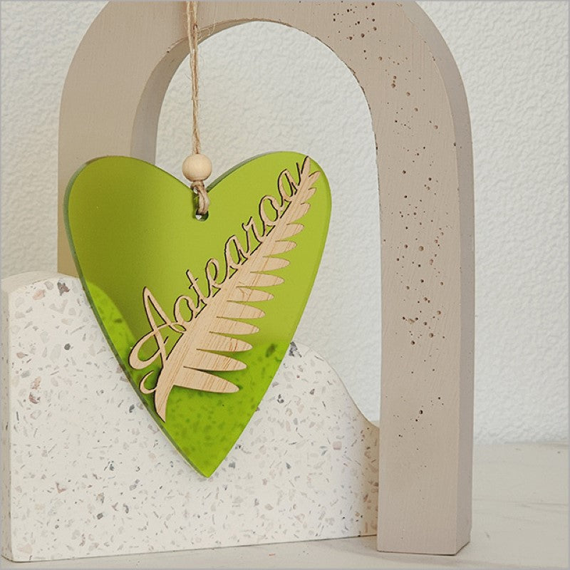 Lime satin acrylic heart ornament featuring a laser-cut silver fern, perfect for holiday decor and gifts.