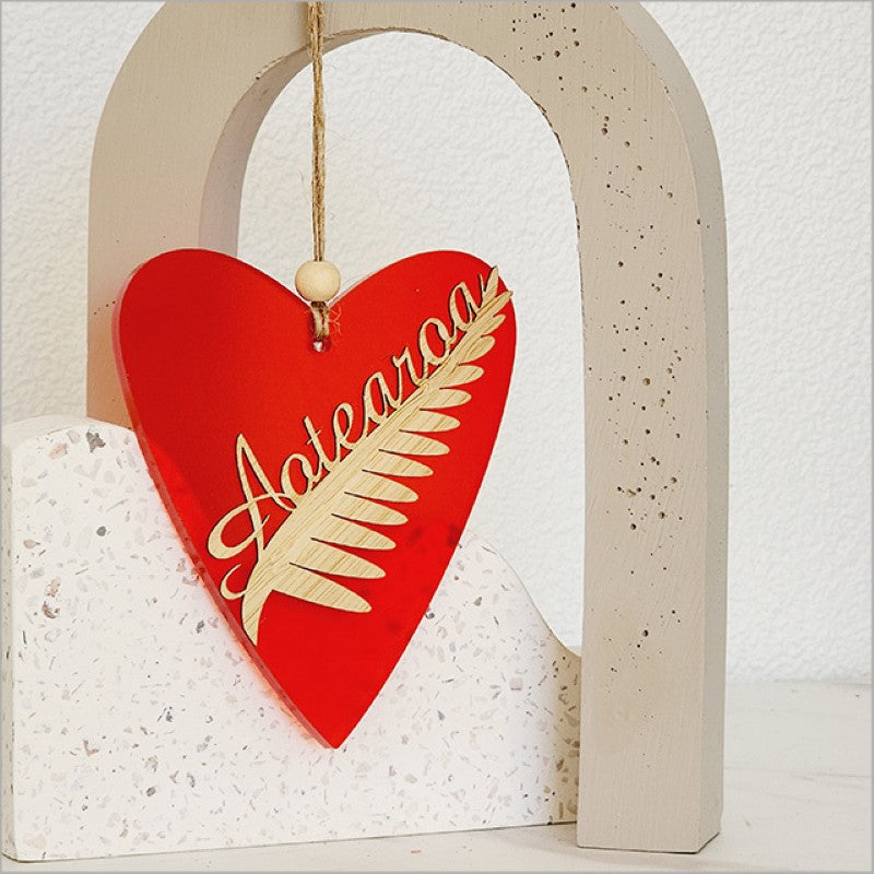 Heart-shaped red satin acrylic ornament featuring the Silver Fern, ideal for holiday decor and gifts.