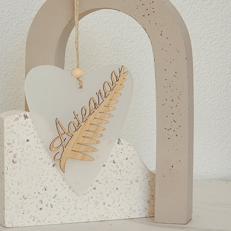 Elegant heart-shaped ornament showcasing a laser-cut silver fern, crafted from white satin acrylic, perfect for decor or gifts.