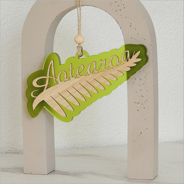Lime satin acrylic hanging ornament featuring a laser-cut silver fern design, perfect for home or office decor.