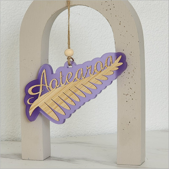 Purple satin acrylic hanging ornament in the shape of a silver fern, made from laser-cut bamboo.