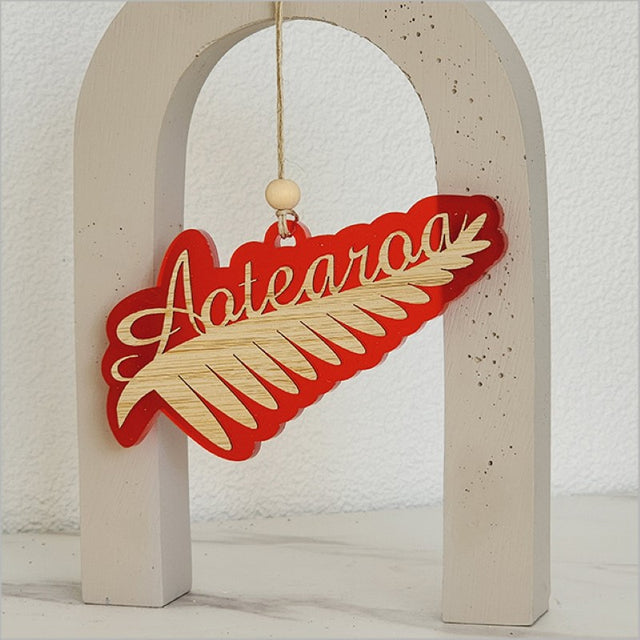 Red satin acrylic hanging ornament featuring an intricately laser-cut silver fern, perfect for home decor or gifts.