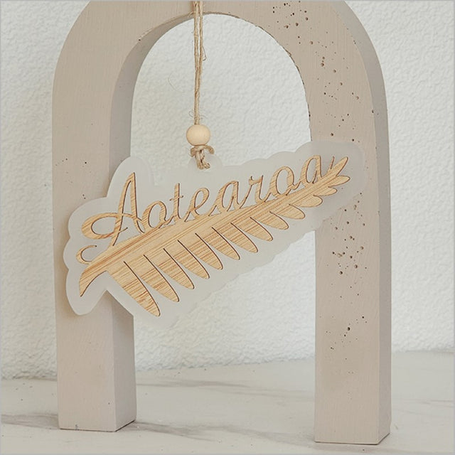 Stunning white satin acrylic hanging ornament featuring a laser cut silver fern, celebrating New Zealand's beauty.